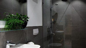 Casa de banho moderna com lavatório branco, sanita e cabine de duche em vidro.