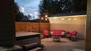 Un jardin avec une terrasse en bois, des meubles d’extérieur et des guirlandes lumineuses.