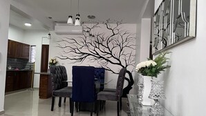 Un espace repas moderne avec une table en verre, deux chaises rembourrées et un élément décoratif mural.