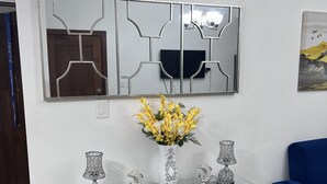 Un salon moderne avec une console en verre, des lampes décoratives et un miroir aux motifs géométriques.