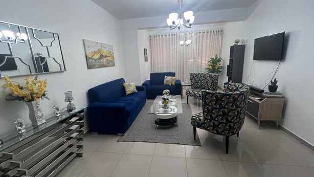 Un salon moderne avec un canapé bleu, un fauteuil à motifs et une table basse.