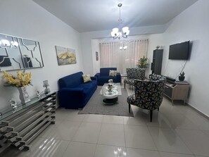Uma sala de estar moderna com um sofá azul, uma poltrona estampada e uma mesa de centro.
