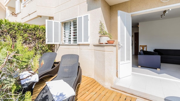 A balcony with two wicker lounge chairs, a small table, and a potted plant. - 2 Bedroom Duplex Apartment in Puerto Pollensa (Puerto Pollensa)