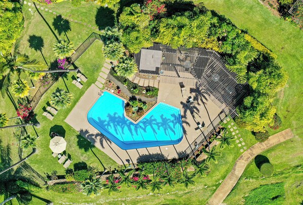 Eine Vogelperspektive zeigt ein Resort mit Pool, Liegebereichen und angelegten Gärten.