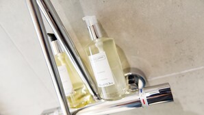 Een badkamer met een chromen kraan en een fles shampoo.