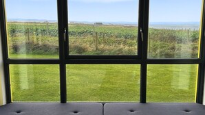 Una habitación con un ventanal grande que da a un campo verde y colinas distantes.
