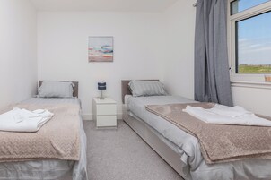 Habitación doble con dos camas, una mesita de noche, una lámpara y una ventana con cortinas.