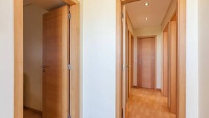 A hallway with wooden doors and a wooden floor. - Beach's House em Moledo (Moledo)