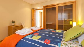 A bedroom with a bed, a wooden wardrobe, a nightstand, and a potted plant. - Beach's House em Moledo (Moledo)