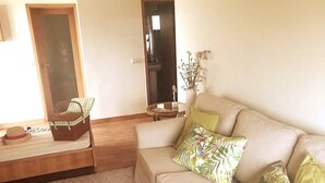 A living room with a beige sofa, a small table, and a wicker basket. - Beach's House em Moledo (Moledo)