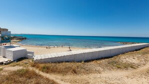 A beach with a concrete barrier, a bar named Ristorante Bar, and a sign for Pizzeria Pino. - 2419 Appartamento Kalepolis (Gallipoli)