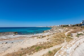 A coastal beach with a stone wall and a clear blue sky. - 2419 Appartamento Kalepolis (Gallipoli)