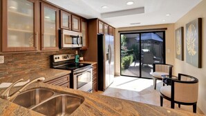 A modern kitchen with granite countertops, stainless steel appliances, and wooden cabinets. - Fabulously Remodeled 2 Bedroom Condo With Beautiful Golf and Mountain Views (La Quinta)