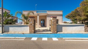 A building with a central entrance, stone pillars, and a blue painted area in front. - 2696 Appartamento La Nave by Barbarhouse (Racale)