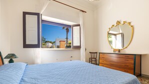 A bedroom with a large bed, a wooden dresser, a mirror, and a window with curtains. - 2696 Appartamento La Nave by Barbarhouse (Racale)