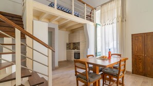 Een moderne keuken met houten kasten, een eettafel met stoelen, en een trap naar een hoger niveau.