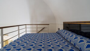 Een slaapkamer met een stapelbed, een houten hoofdbord, een witte muur en een trap.
