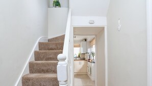A staircase leading to a kitchen with white cabinets and a wooden floor. - Crew House (Dartmouth)
