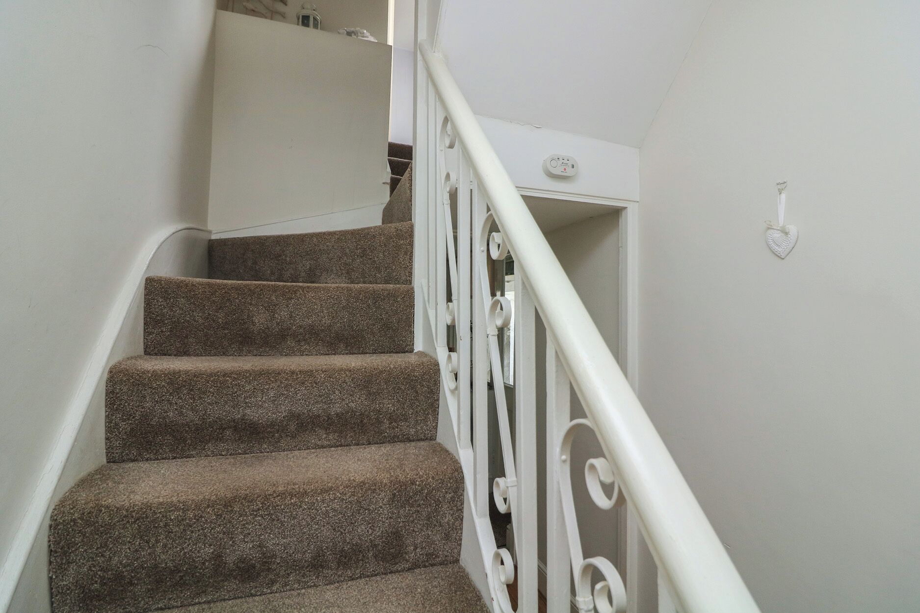 A staircase with carpeted steps and white metal railings.