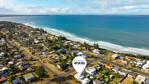 Luftaufnahme einer Küstenwohngegend mit Häusern, Straßen und einem Strand.