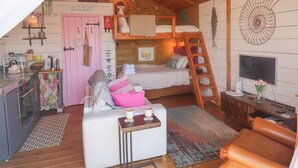Une chambre mansardée chaleureuse, avec un lit superposé, un bureau, une chaise et un téléviseur.
