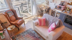 Un salon chaleureux avec un fauteuil en cuir, un canapé blanc agrémenté de coussins roses, une table basse et un tapis.