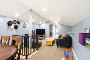 Relax in this stylish living room with a dining table, sofa, TV, and bookshelf.