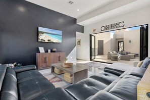 A modern living room with a large sofa, a coffee table, and a television mounted on the wall.