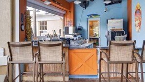 Ein Restaurant mit Theke, Stühlen, Deckenventilatoren und einem Fernseher an der Wand.
