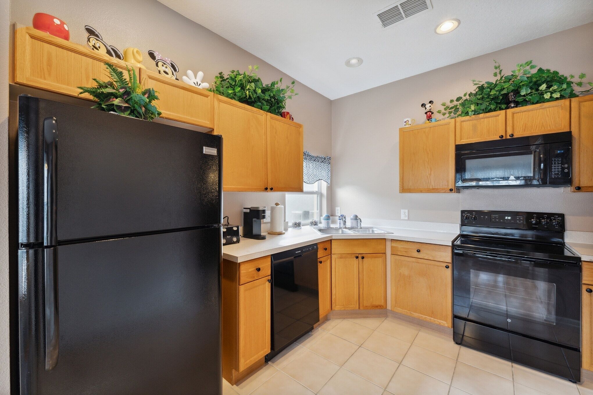 A kitchen with wooden cabinets, a black refrigerator, a dishwasher, a microwave, and an oven.