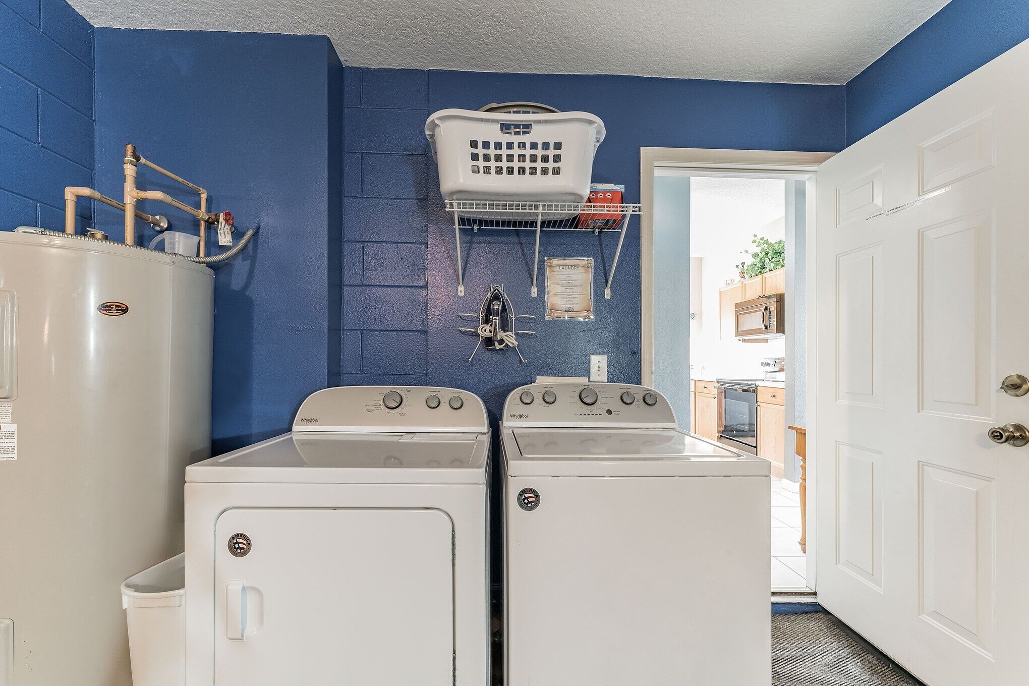 A laundry room with two front-loading washers, a white refrigerator, and a blue wall.