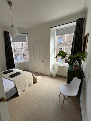 Ein Schlafzimmer mit einem Bett, einem Sessel, einer Zimmerpflanze und einer Heizung.