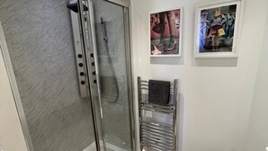 Un baño moderno con cabina de ducha de vidrio, inodoro y dos cuadros en la pared.