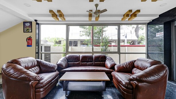 Quarto moderno com sofá de couro, mesa de centro de madeira e ventoinha de teto.