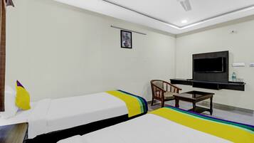 Habitación de hotel con dos camas, un escritorio, una silla, un televisor y un ventilador de techo.
