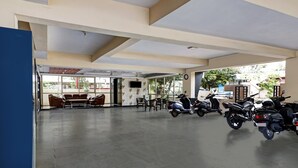 Amplo espaço interno com área de estar, ventilador de teto e várias motocicletas estacionadas.