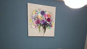 Ein Schlafzimmer mit einem Bett, zwei Nachttischen, einem Wandbild und zwei aufgerollten Handtüchern auf dem Bett.