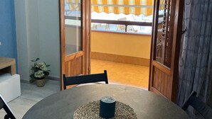 Ein Zimmer mit einem runden Tisch, Stühlen und Blick durch eine Holztür mit Streifenstoren.