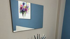 Ein moderner, minimalistischer Empfangstresen mit einem gerahmten Kunstwerk darüber und einer klaren Glasvase mit Stiften auf dem Tisch.