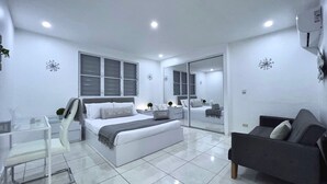 Um quarto moderno com cama, mesa de cabeceira, cadeira e sofá.