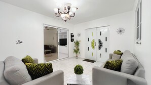 Uma sala de estar moderna com um conjunto de sofá, uma planta em vaso e arte decorativa na parede.