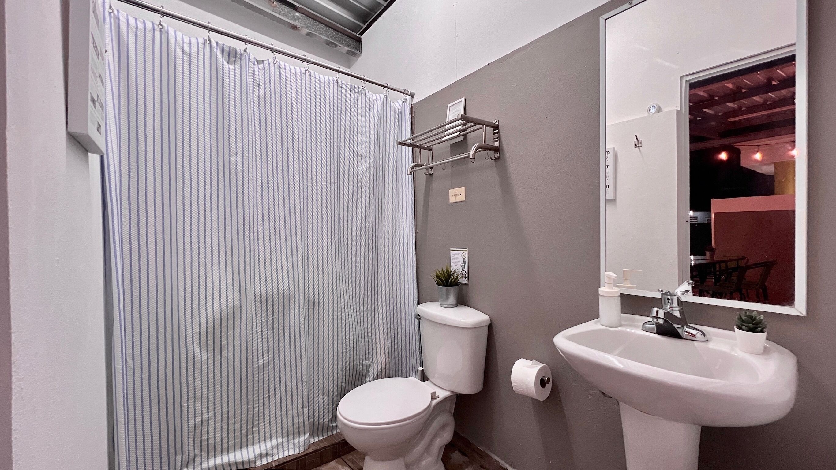 Un baño con inodoro, lavamanos y cortina de ducha.