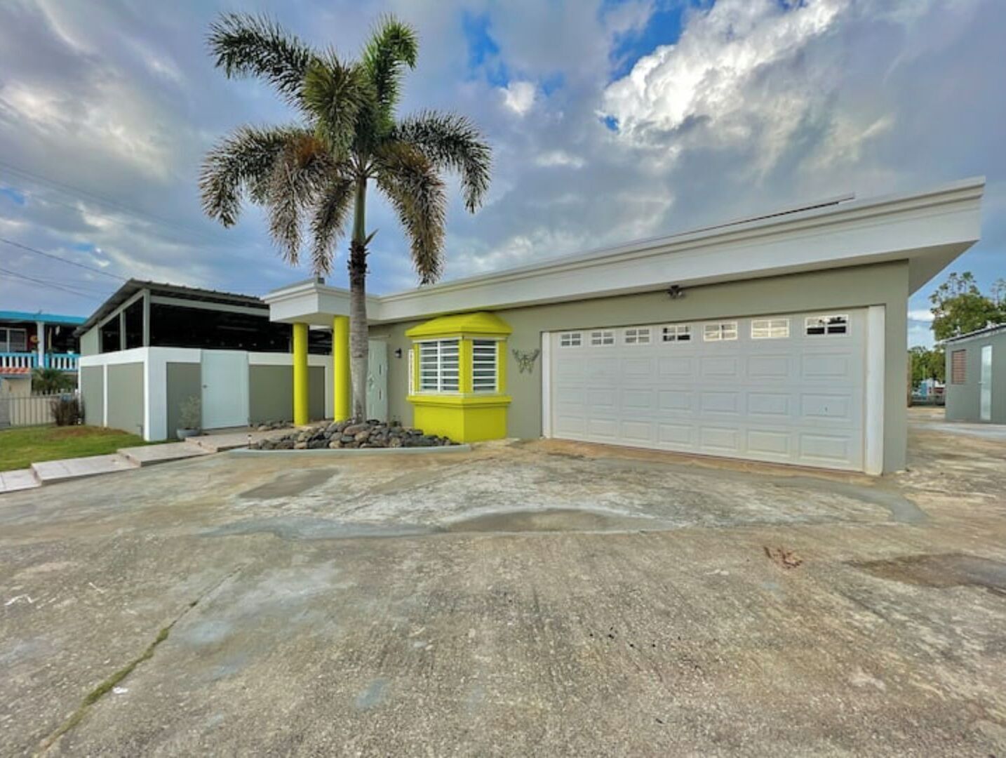 A modern house with a garage, a palm tree, and a small garden area.