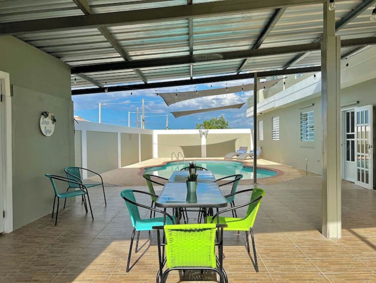 A covered patio area with a pool, outdoor seating, and a view of the sky.