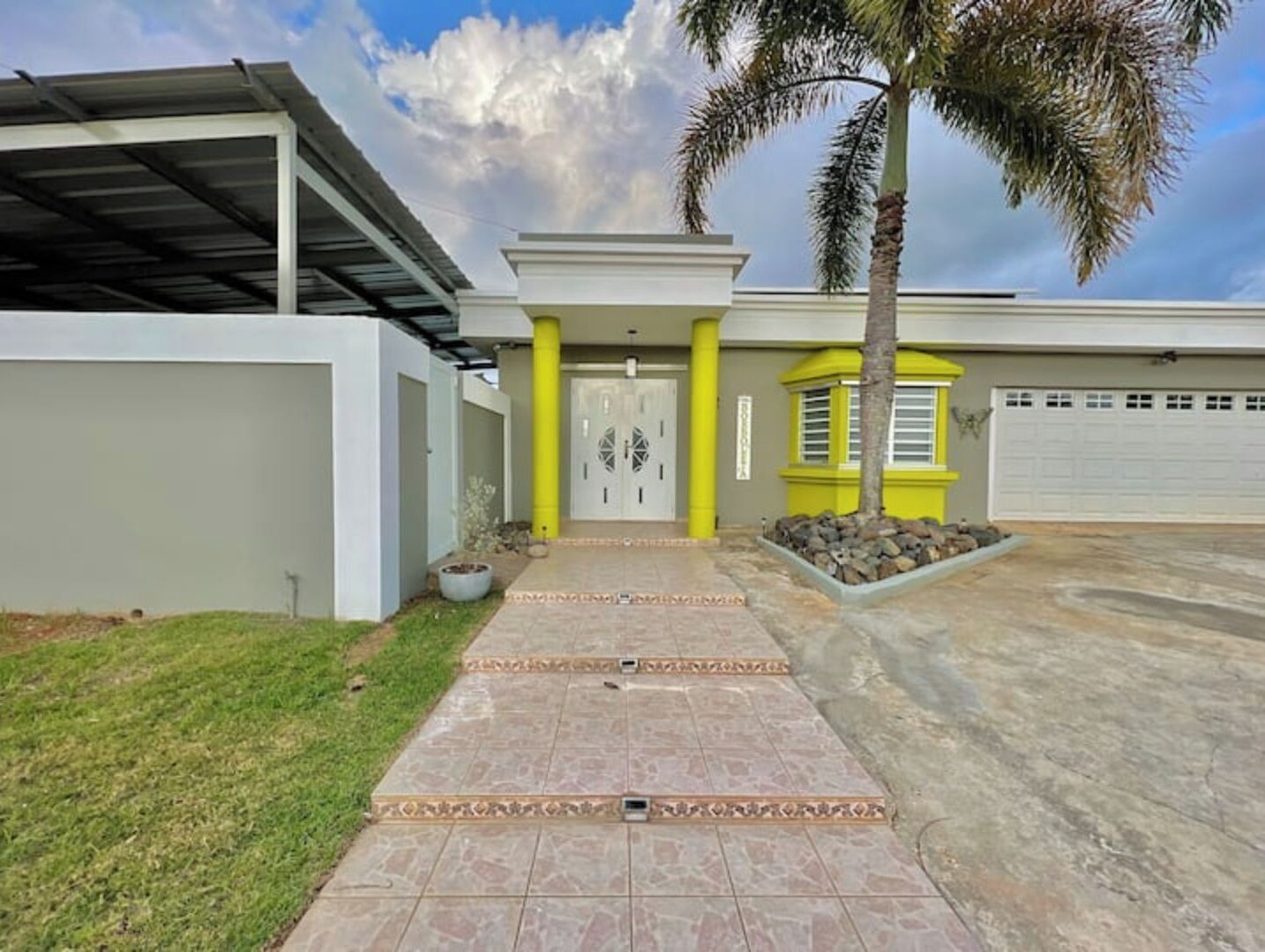 Een modern huis met een overdekte patio, een garage en een verzorgd gazon.