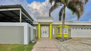 Uma casa moderna com varanda coberta, garagem e gramado bem cuidado.
