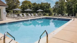 A swimming pool with lounge chairs and umbrellas, surrounded by trees. - Lovely 2-Bdrm unit with pool. Home away from home. (Naperville)