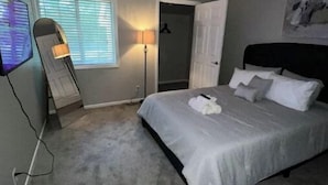 A bedroom with a bed, a TV, a desk, and a door. - Lovely 2-Bdrm unit with pool. Home away from home. (Naperville)