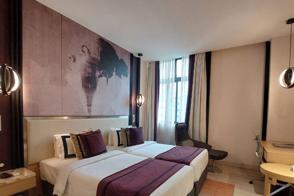 A hotel room with two beds, a desk, and a chair.