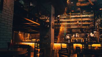A dimly lit bar with wooden furniture and shelves stocked with bottles.